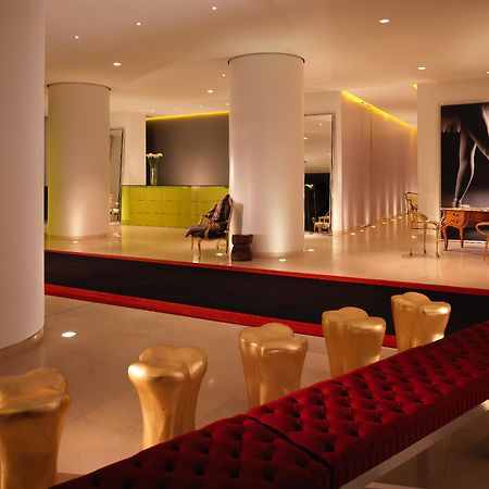 فندق سانت مارتنز لاين لندن المظهر الخارجي الصورة The photo shows a modern and stylish interior space, possibly a lobby or a lounge area. It features sleek white pillars and a polished floor, illuminated by soft ambient lighting. On one side, there is a green seating area, while on the opposite side